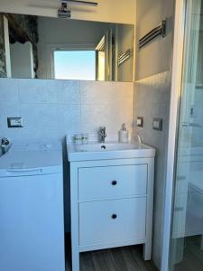 een witte badkamer met een wastafel en een spiegel bij Il Vicolo agli Orti - Centro storico - Lake Como in Bellano