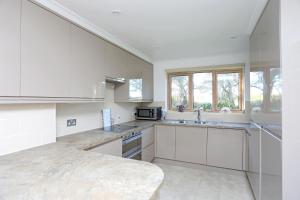 uma grande cozinha com armários brancos e um lavatório em Picturesque Family Hideaway Chipping Ongar Essex em Fyfield