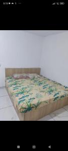a bed with a floral comforter on top of it at Casa de praia Jacumã in Conde