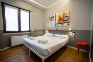 um quarto com uma grande cama branca e uma cadeira vermelha em Babila Hostel & Bistrot em Milão