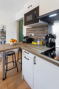 a kitchen with white cabinets and a wooden counter top at Joli studio - Parking Privé - WIFI Très Haut Débit - Au calme in Nantes