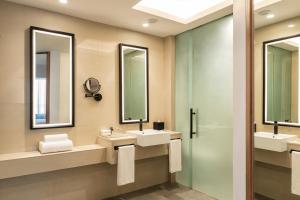 a bathroom with two sinks and two mirrors at Sheraton Mall of the Emirates Hotel, Dubai in Dubai