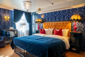 1 dormitorio con 1 cama con paredes azules y almohadas rojas en Charmante - Skostredet Hôtel, en Bergen