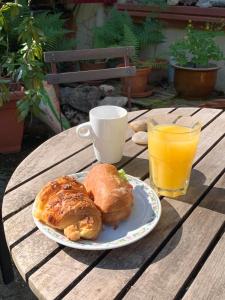 Ferrette的住宿－Chambres d'Hôtes Le Felseneck - NOUVEAU PROPRIÉTAIRE - NEW MANAGEMENT，木桌上放着一盘糕点和一杯橙汁