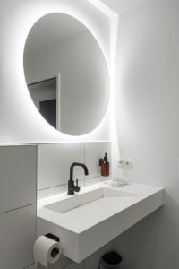 a white bathroom with a sink and a mirror at Village by Maier - kontaktloser Check-in in Hohenems