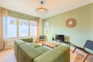 een woonkamer met een groene bank en een televisie bij 3 bedroom house with garden near Lille + garage in Lambersart