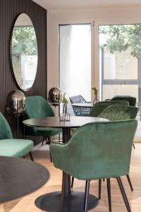 una stanza con sedie verdi, tavolo e specchio di Village by Maier - kontaktloser Check-in a Hohenems