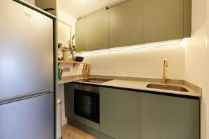 a kitchen with green cabinets and a sink and a refrigerator at The North Notting Hill Crib - Bright 1BDR Flat in London
