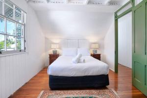 a bedroom with a bed with white sheets and a window at Charming heritage house in the heart of the city in Brisbane