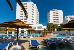 a swimming pool with chairs and umbrellas and buildings at AL Sunset in Albufeira