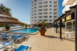 a swimming pool with blue chairs and a building at AL Sunset in Albufeira