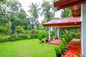 ein Haus mit einer roten Veranda und einem grünen Hof in der Unterkunft Villa Ravichini in Polonnaruwa