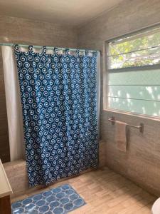 La salle de bains est pourvue d'une douche avec un rideau de douche bleu et blanc. dans l'établissement Brisas Verdes. Increíble espacio con alberca climatizada, à Temixco