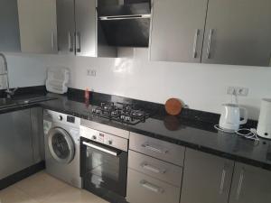 een keuken met een fornuis en een wasmachine bij appartement mdiq tetouan, 2 chambres 1 double salon in M'diq