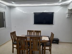 een eetkamer met een tafel en stoelen en een projectiescherm bij appartement mdiq tetouan, 2 chambres 1 double salon in M'diq