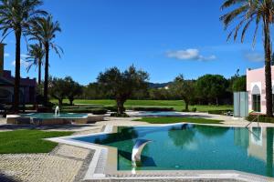 - une piscine dans une cour avec des palmiers dans l'établissement Pestana Sintra Golf Resort & SPA Hotel, à Sintra