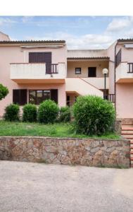 a house with a stone wall in front of it at Casa Mediterraneo Santa Teresa di Gallura in Porto Pozzo