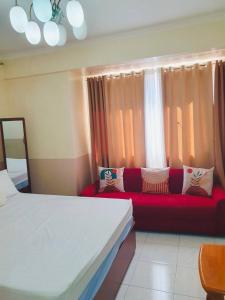 - une chambre avec un canapé rouge en face d'une fenêtre dans l'établissement BAGUIO CONDO ALBERGO HOTEL by DEI GRATIA, à Baguio