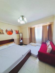 - une chambre avec deux lits et un canapé rouge dans l'établissement BAGUIO CONDO ALBERGO HOTEL by DEI GRATIA, à Baguio