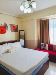 - une chambre avec un grand lit blanc et un canapé rouge dans l'établissement BAGUIO CONDO ALBERGO HOTEL by DEI GRATIA, à Baguio