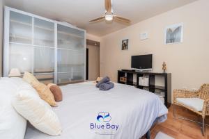 Un dormitorio con una gran cama blanca y un televisor. en Al Alba Townhouse with Community Pool and Padel, en La Herradura
