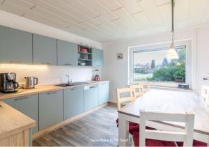 a kitchen with blue cabinets and a table and a window at Haus Roter Sand in Hooksiel in Wangerland