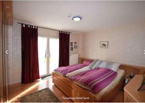 a bedroom with a bed with purple sheets and a window at Haus Roter Sand in Hooksiel in Wangerland