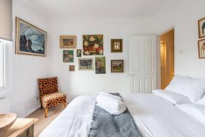 biała sypialnia z łóżkiem i krzesłem w obiekcie Chic Top Floor Apartment in the heart of Notting Hill Ladbroke Grove w Londynie