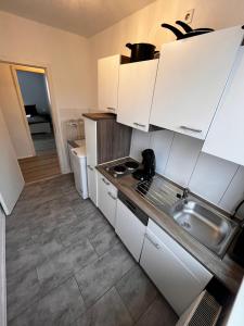 una pequeña cocina con armarios blancos y fregadero en Tolle Monteursunterkunft für 6 Personen en Ennepetal