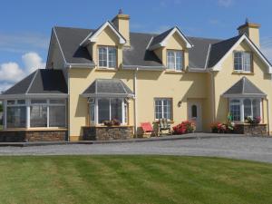 a yellow house with a lawn in front of it at Cill Chiarain B&B in Ballybunion