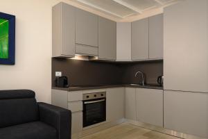 eine Küche mit weißen Schränken und einem Sofa in der Unterkunft Classbnb - Bilocale di design in zona Sempione in Mailand