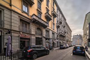 eine Stadtstraße mit Autos neben Gebäuden in der Unterkunft Classbnb - Bilocale di design in zona Sempione in Mailand