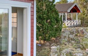 una casa con un porche con un árbol al lado en Amazing Home In Mariefred With Kitchen en Mariefred