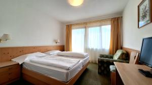 a hotel room with a bed and a chair and a television at Hotel Hubertushof in Vipiteno