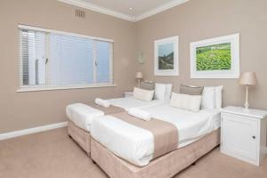 Habitación blanca con 2 camas y 2 ventanas en 2 Bedroom Apartment With Amazing City Views, en Ciudad del Cabo