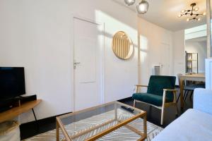 uma sala de estar com uma mesa de café em vidro e uma cadeira verde em Renovated 3 bedroom house with terrace em Tourcoing