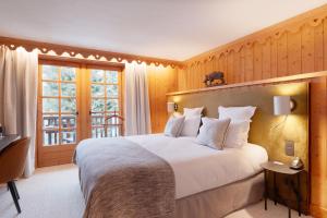 Un dormitorio con una gran cama blanca y una ventana en La Ferme du Golf en Megève