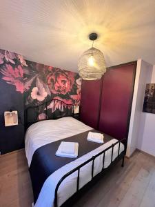 - une chambre avec un grand lit orné d'un mur fleuri dans l'établissement Le Loly, à Clermont-Ferrand