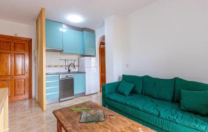 a living room with a green couch and a kitchen at Lovely Apartment In Puerto De Mazarrón in Puerto de Mazarrón