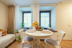 Cozy Suite Roomita في فيلنيوس: غرفة طعام مع طاولة بيضاء وكراسي
