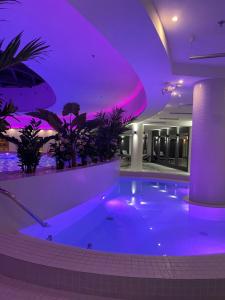 a large swimming pool with purple lighting in a building at Hanza Tower Apartament Times Square in Szczecin
