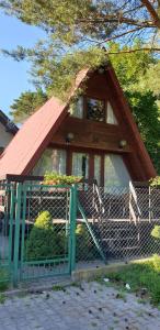 a small house with a red roof and a gate at SOLO in Łukęcin