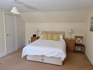 1 dormitorio con 1 cama blanca grande con almohadas amarillas en The Coach House - Bargany en Girvan