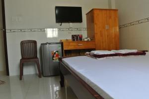 a room with a refrigerator and a chair and a television at Nhà Nghỉ HOA LÝ in Chau Doc
