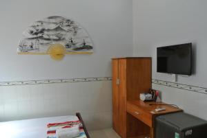 a room with a bed and a tv on a wall at Nhà Nghỉ HOA LÝ in Chau Doc