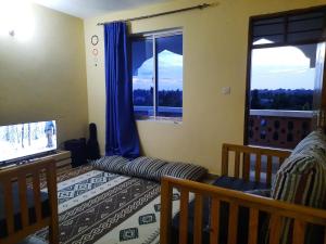 sypialnia z łóżkiem i telewizorem oraz 2 oknami w obiekcie Kilifi Homes apt E-5 w mieście Kilifi