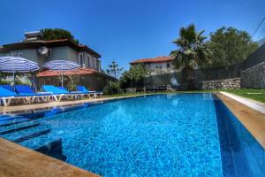 - une piscine avec des chaises et des parasols à côté d'une maison dans l'établissement Villa Şans, à Fethiye
