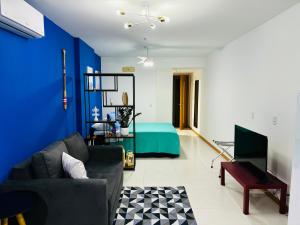 ein Wohnzimmer mit einem Sofa und einer blauen Wand in der Unterkunft Studio Acqua - estilo no melhor bairro da cidade in Niterói
