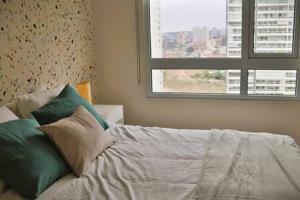 1 dormitorio con cama con almohadas y ventana en Precioso Depto en el centro de Concón 1D1B con Piscina Servicio HOM 0115 en Concón