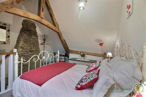 una camera da letto con un grande letto bianco con cuscini rossi di Le parfum des fleurs a Plussulien